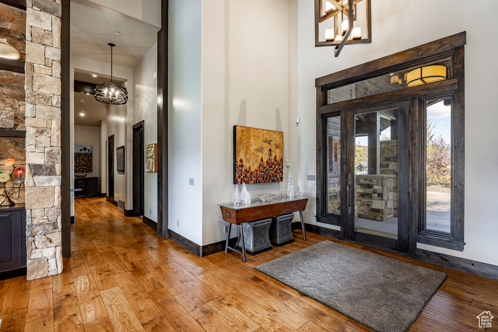 Entryway with a towering ceiling, a chandelier, wood-type flooring, and baseboards