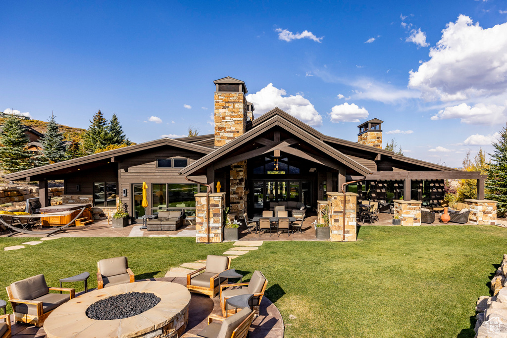 Rear view of property featuring a chimney, a patio, and stone siding