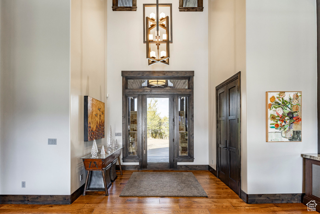 Entryway featuring a towering ceiling, a chandelier, wood finished floors, and baseboards
