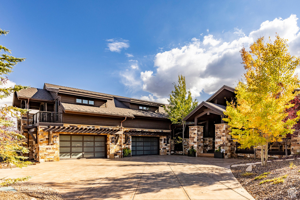 View of front of property featuring an attached garage, driveway, and stone siding