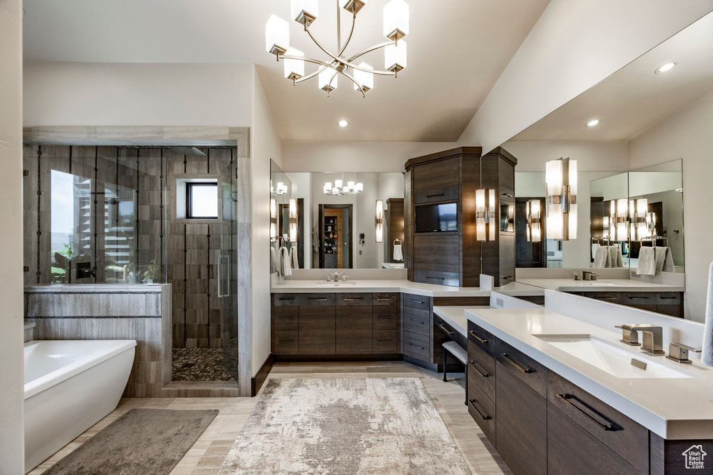 Bathroom featuring a chandelier, a stall shower, a freestanding bath, two vanities, and recessed lighting