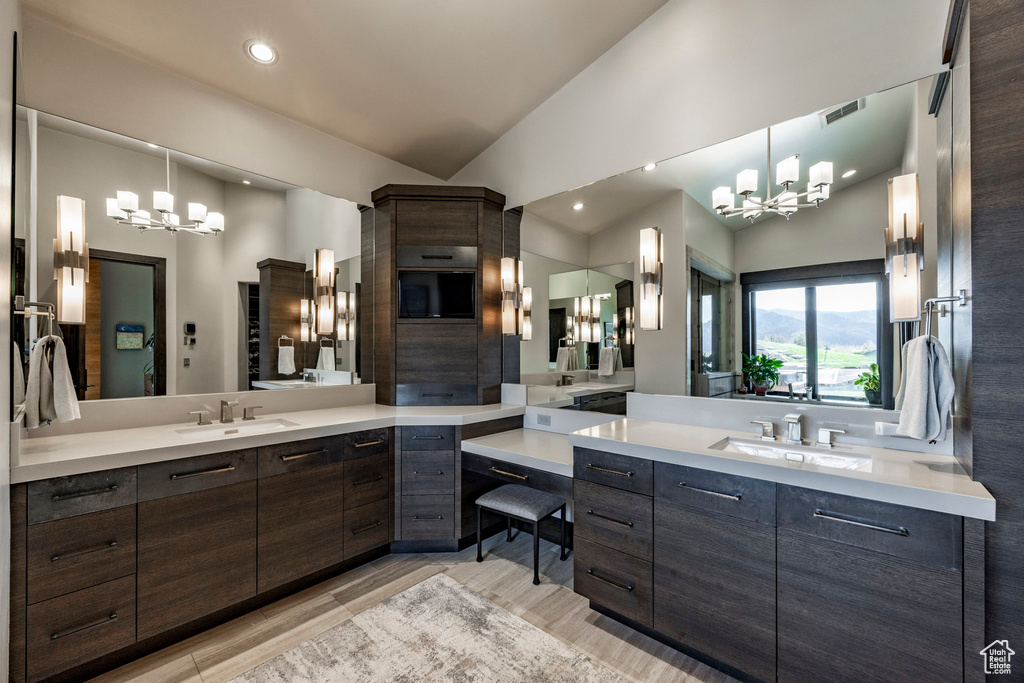 Bathroom with a chandelier, two vanities, vaulted ceiling, and recessed lighting