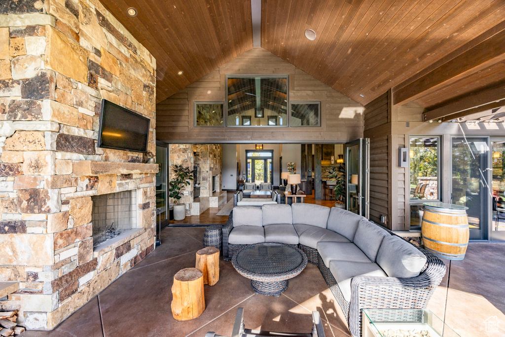 Living room with wood ceiling, high vaulted ceiling, and an outdoor stone fireplace