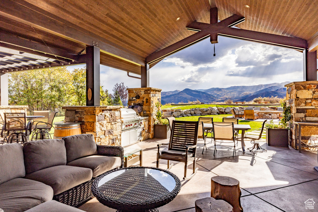 View of patio / terrace with area for grilling, a mountain view, an outdoor living space with a fireplace, outdoor dining area, and ceiling fan