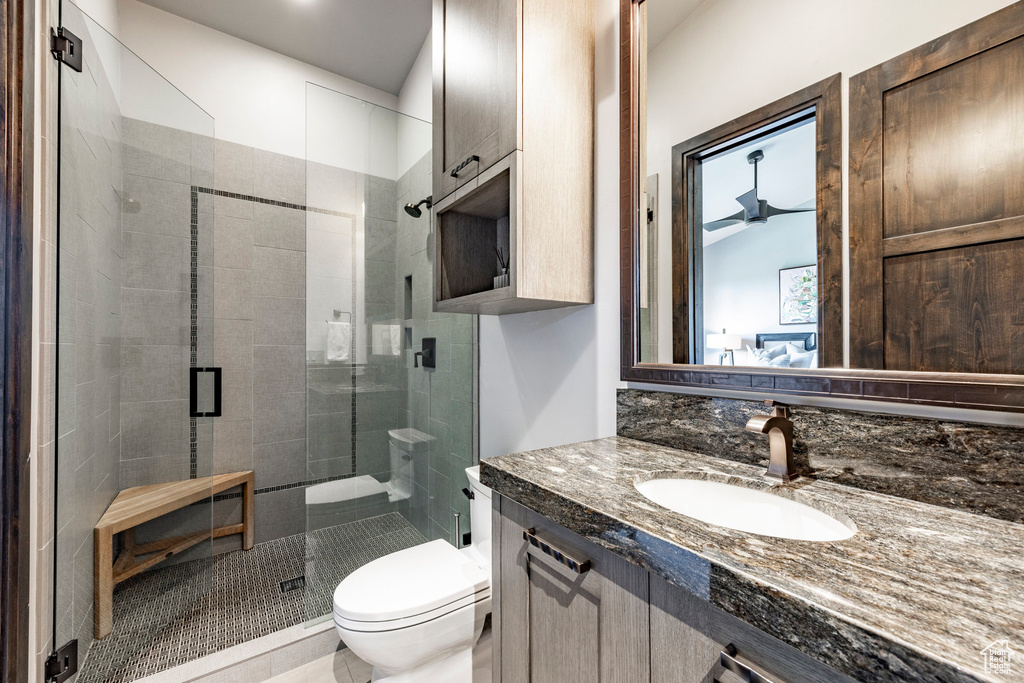 Bathroom with toilet, vanity, and a stall shower