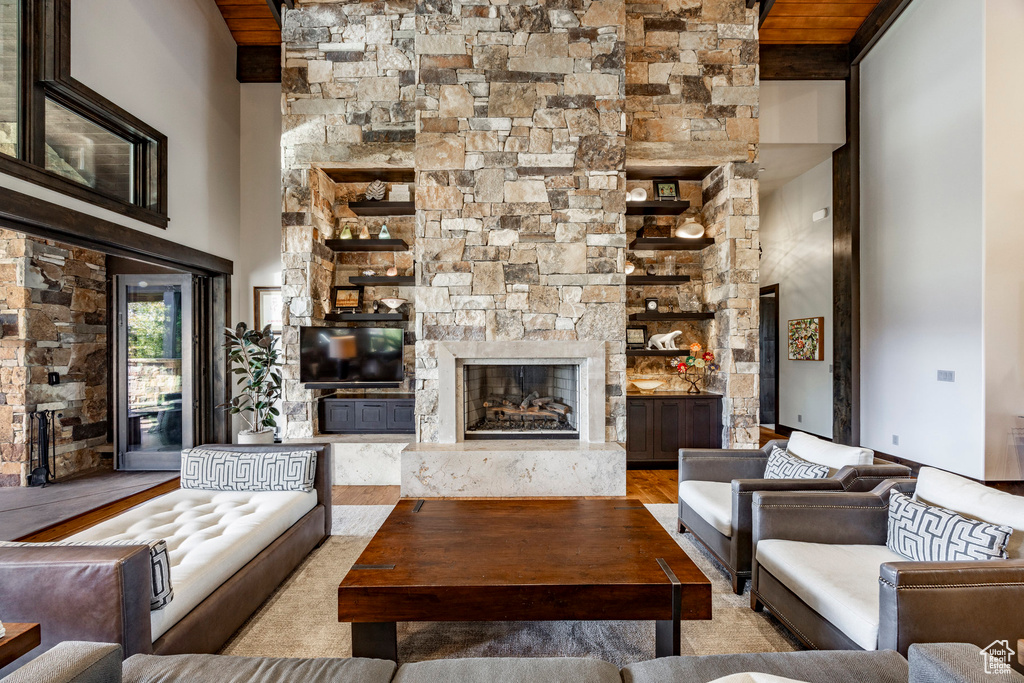 Living room with a high end fireplace, a towering ceiling, and wood finished floors