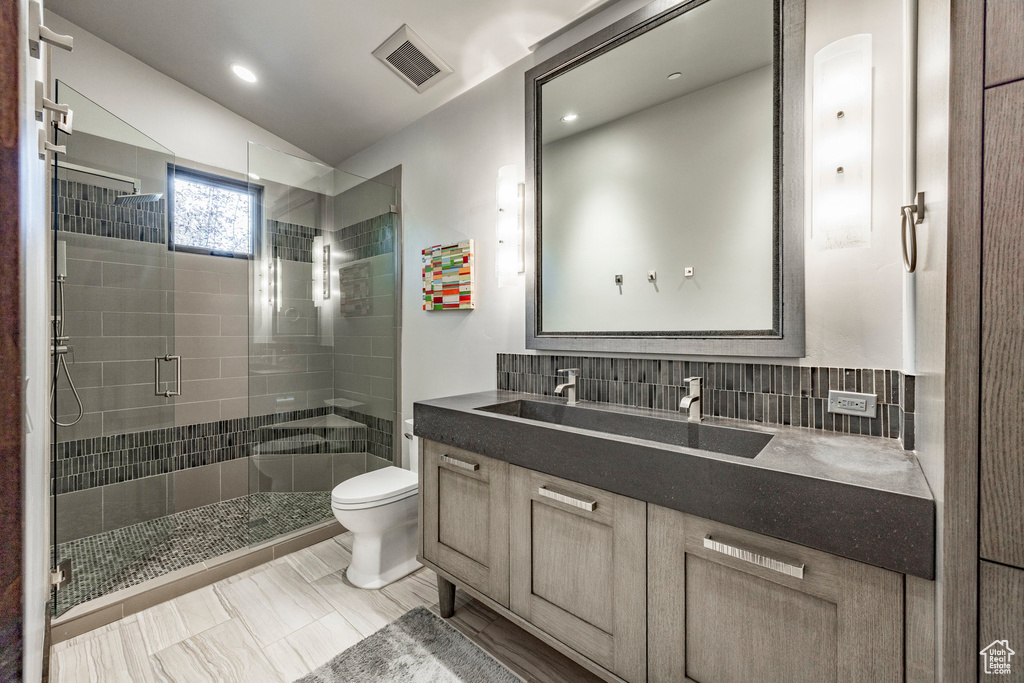 Full bathroom with toilet, a stall shower, vanity, tasteful backsplash, and recessed lighting