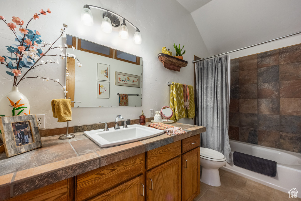 Full bathroom featuring tile patterned floors, toilet, shower / bath combo with shower curtain, vaulted ceiling, and vanity