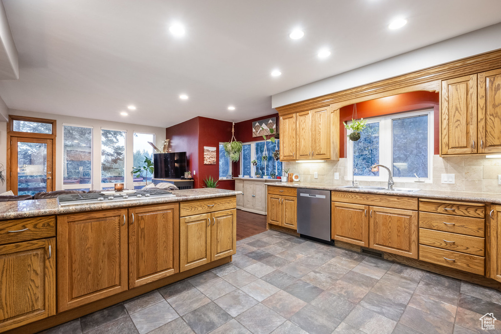 Kitchen with sink, light stone counters, stainless steel appliances, and tasteful backsplash