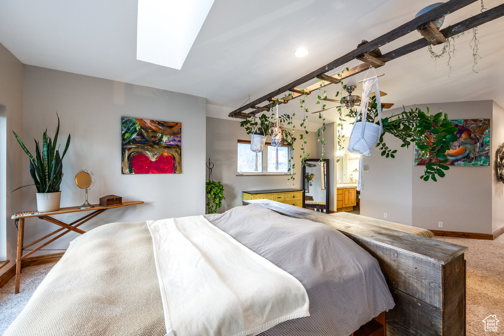 Bedroom featuring a skylight, ensuite bath, and carpet