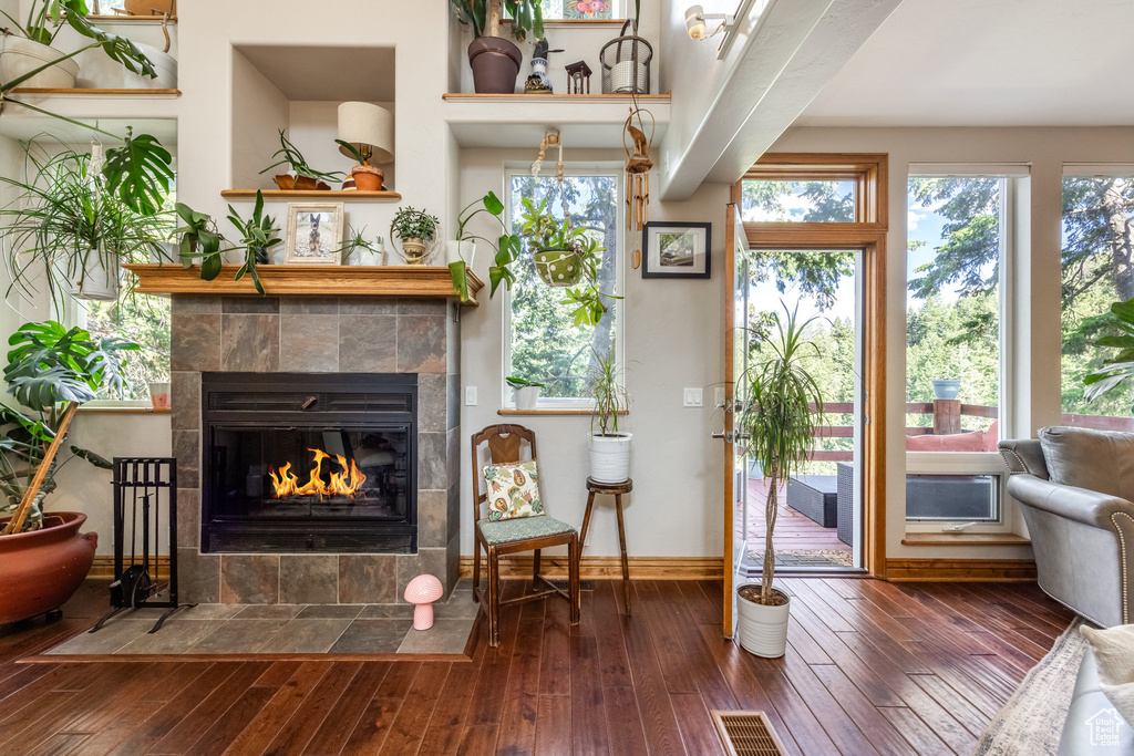 Living area with a tile fireplace, hardwood / wood-style flooring, and plenty of natural light