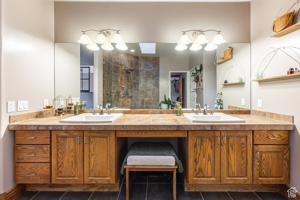 Bathroom featuring vanity, tile patterned floors, and tiled shower