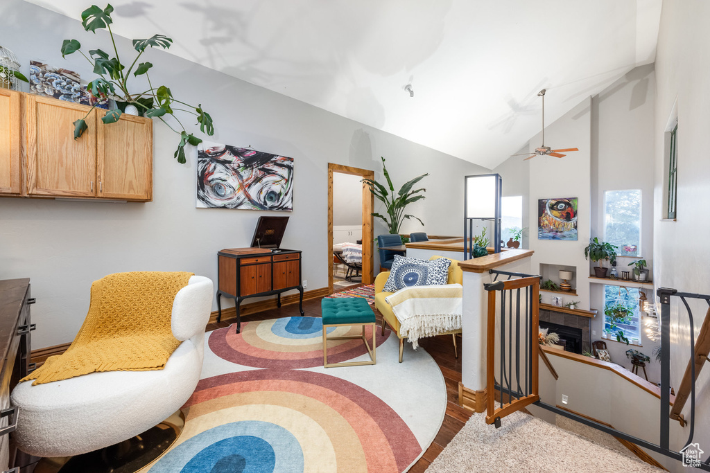 Living room with hardwood / wood-style floors, a tiled fireplace, high vaulted ceiling, and ceiling fan