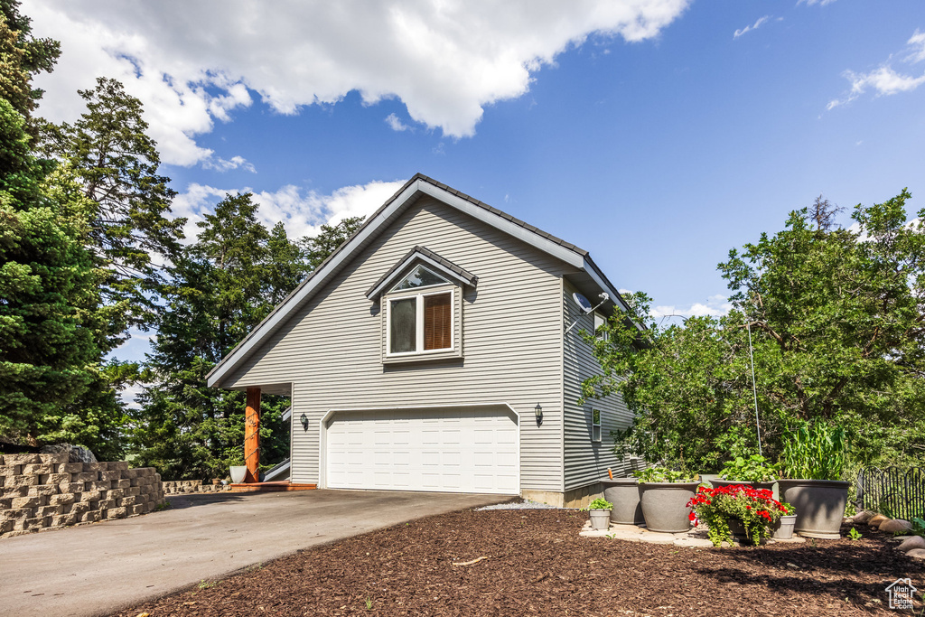 View of property exterior with an attached garage and driveway