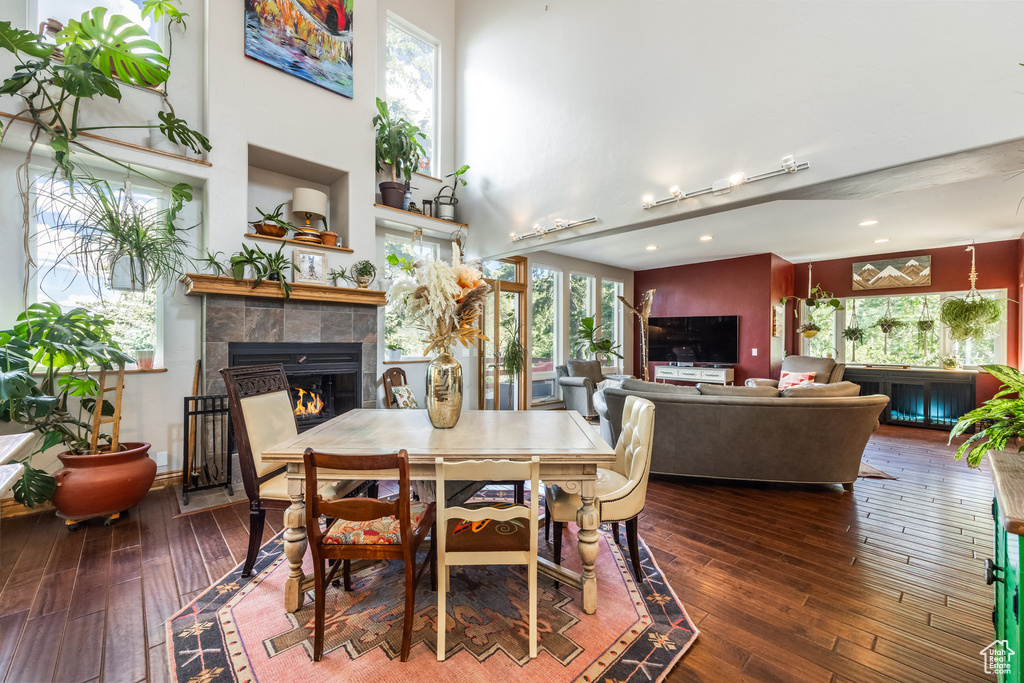 Dining area with a fireplace, hardwood / wood-style floors, healthy amount of natural light, recessed lighting, and a high ceiling