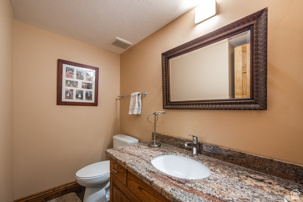 Bathroom featuring vanity, toilet, and a textured ceiling