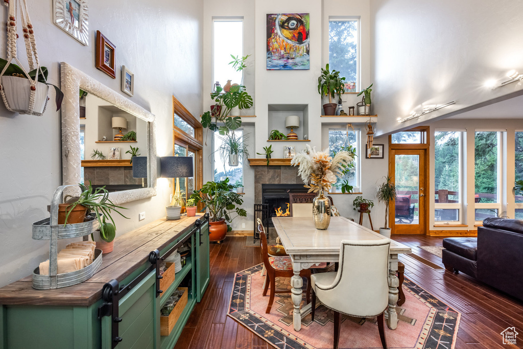 Dining room with dark wood-type flooring and a tiled fireplace
