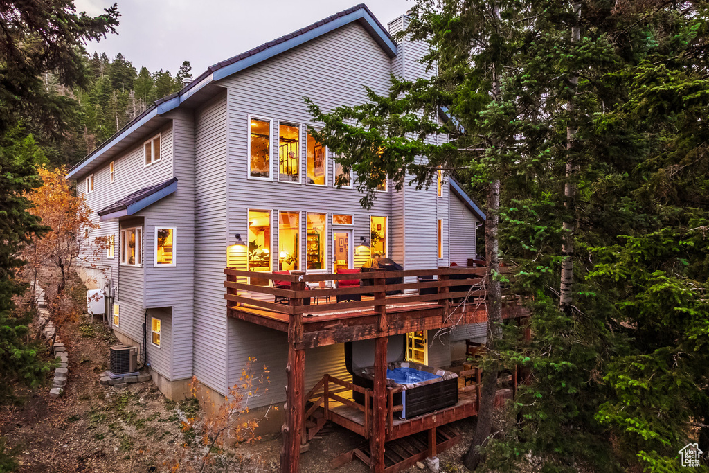 Back of house featuring a wooden deck and central AC unit