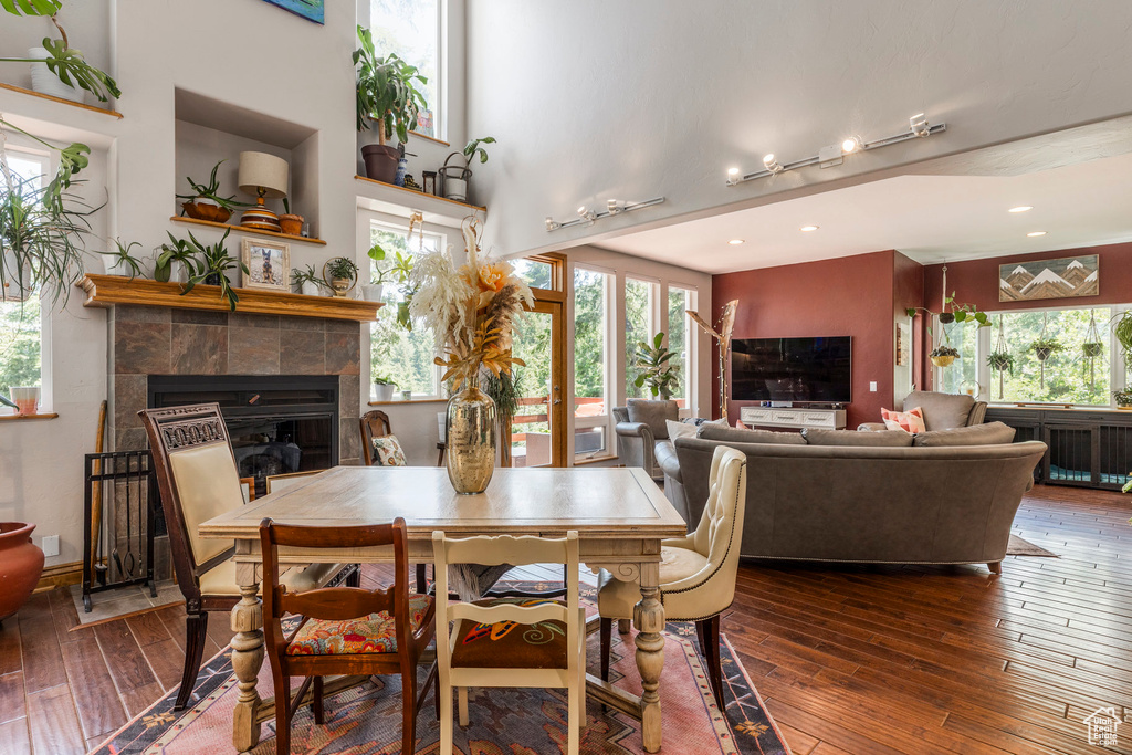 Dining space with healthy amount of natural light, hardwood / wood-style flooring, a tiled fireplace, and recessed lighting