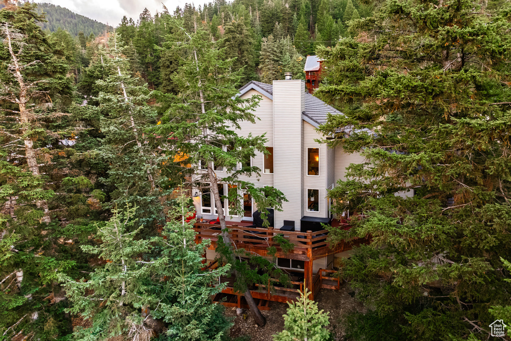 View of home's exterior with a chimney, a view of trees, and a deck