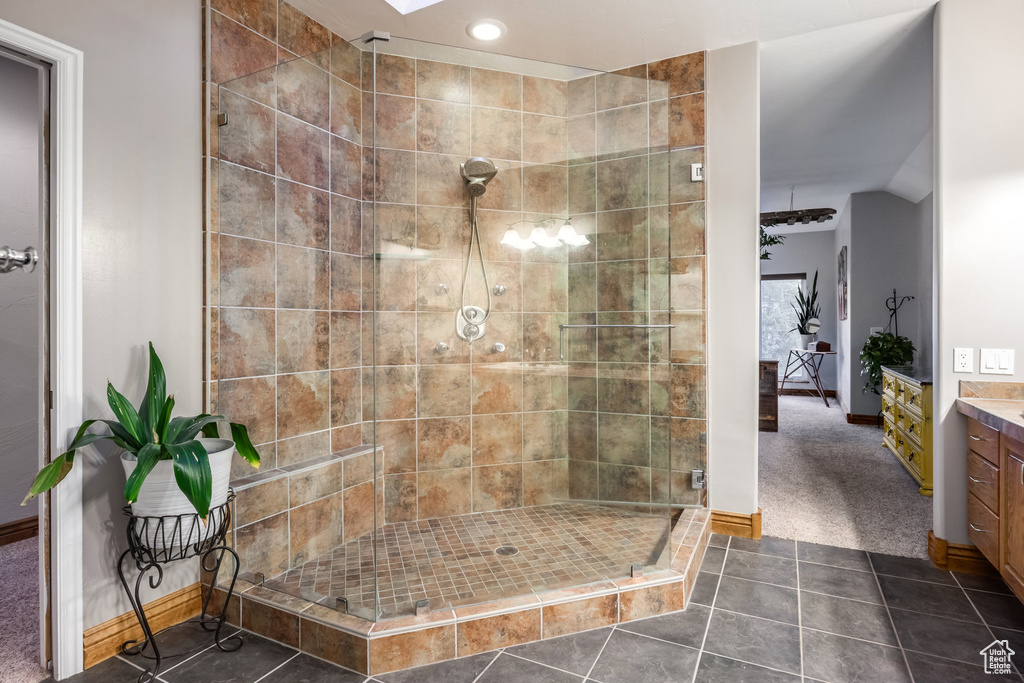 Bathroom with vanity, tile patterned floors, a skylight, and tiled shower