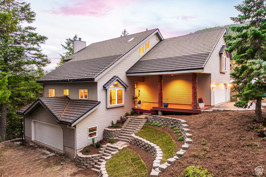 Rustic home with a tiled roof, a chimney, and driveway