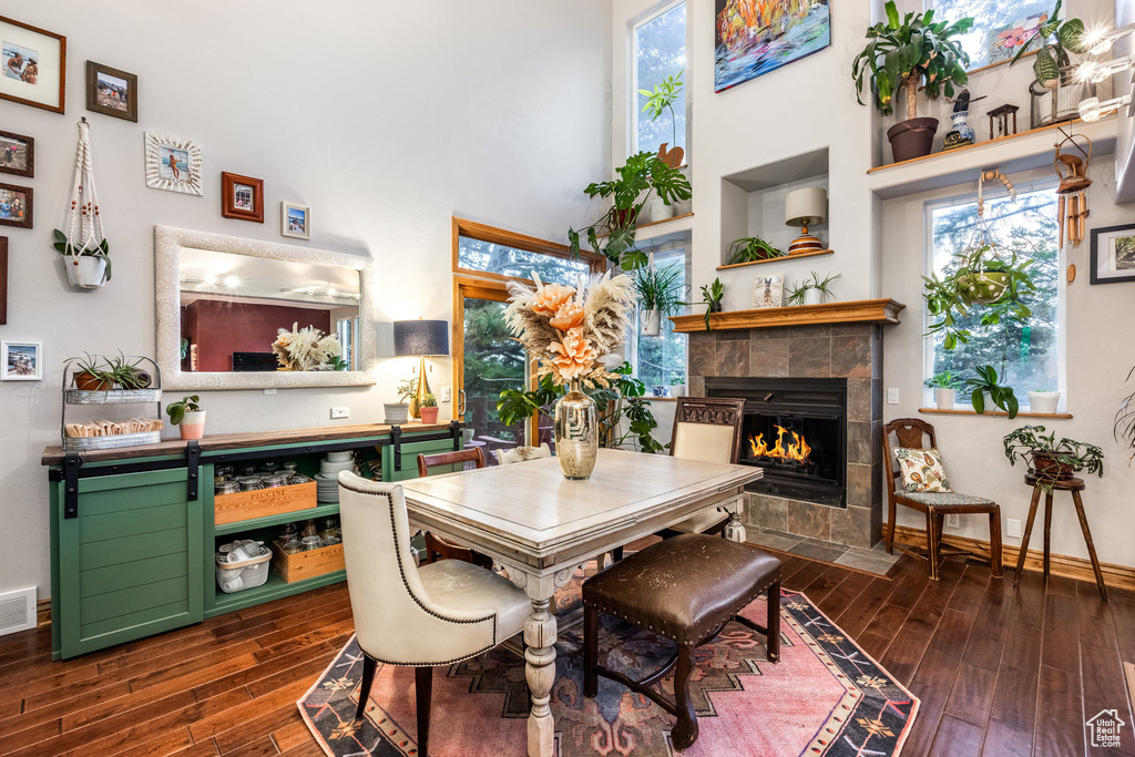 Dining area featuring a high ceiling, a tiled fireplace, and dark hardwood / wood-style floors