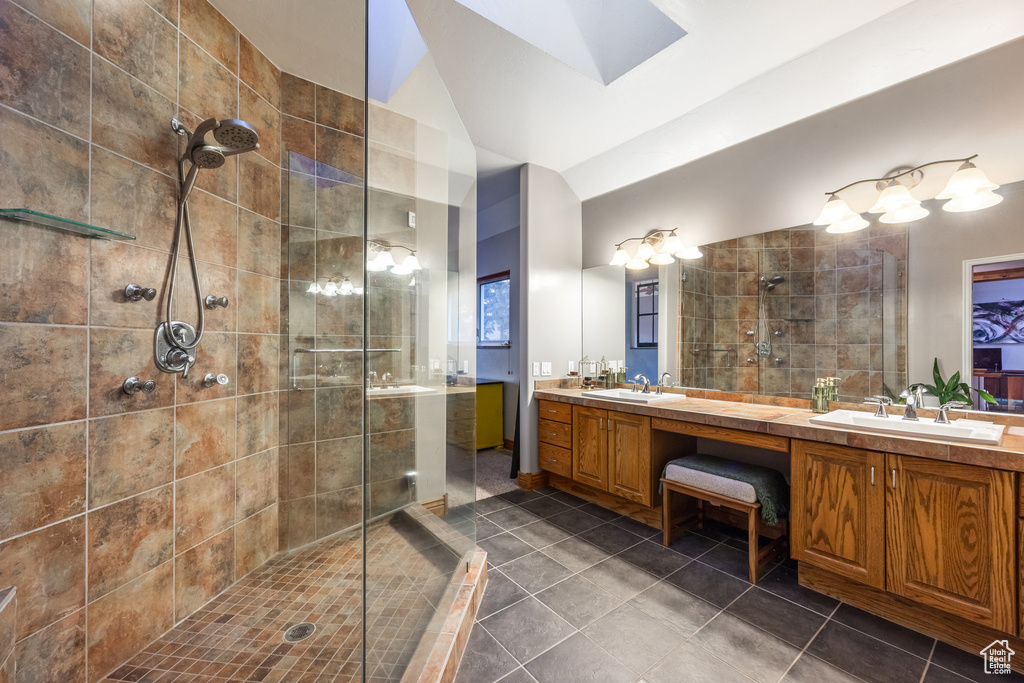 Bathroom featuring vanity, tile patterned floors, a tile shower, and vaulted ceiling