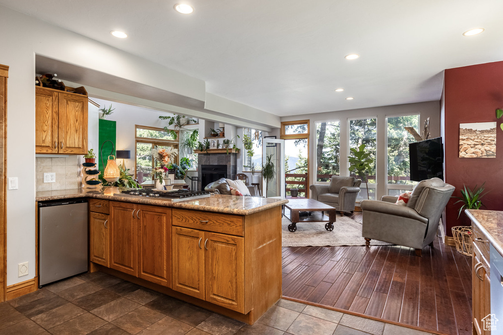 Kitchen with dishwasher, a peninsula, open floor plan, recessed lighting, and a tile fireplace