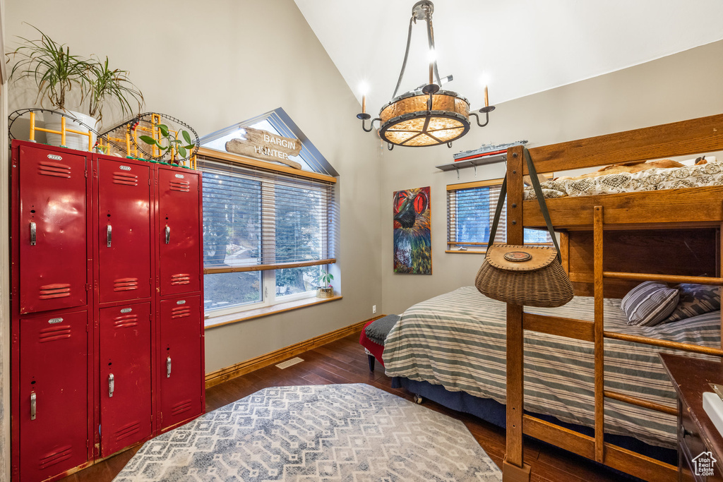 Bedroom featuring dark wood-type flooring, a notable chandelier, and lofted ceiling