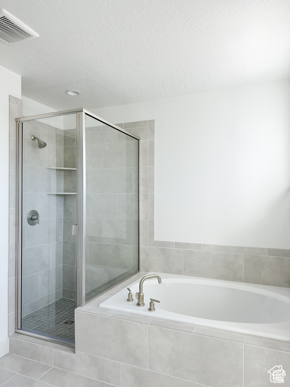 Bathroom with tile patterned floors, a textured ceiling, and shower with separate bathtub