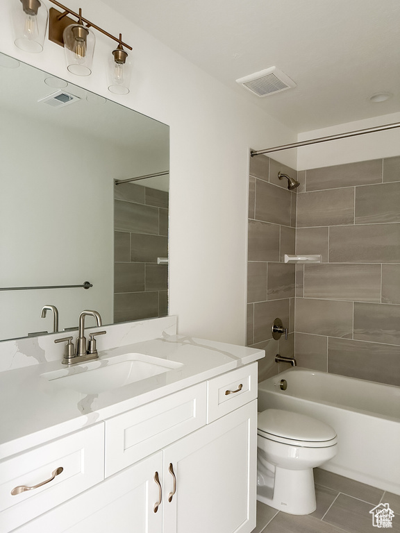 Full bathroom with toilet, tiled shower / bath combo, vanity, and tile patterned floors