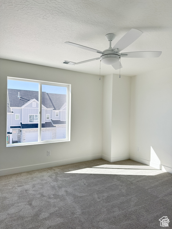 Empty room featuring a textured ceiling, carpet floors, and ceiling fan