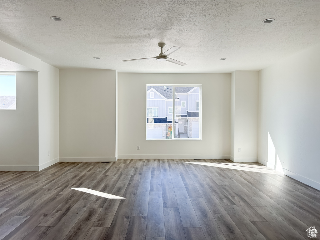 Empty room with a textured ceiling, hardwood / wood-style flooring, and ceiling fan