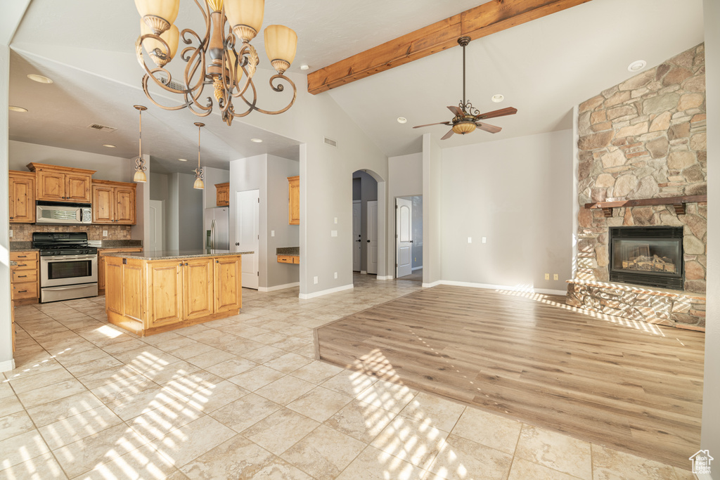 Kitchen with beam ceiling, a fireplace, ceiling fan with notable chandelier, light hardwood / wood-style floors, and stainless steel appliances