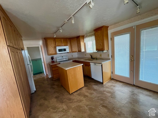 Kitchen with white appliances, french doors, sink, and a kitchen island