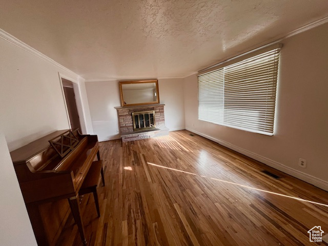 Unfurnished living room featuring crown molding, hardwood / wood-style flooring, and a textured ceiling