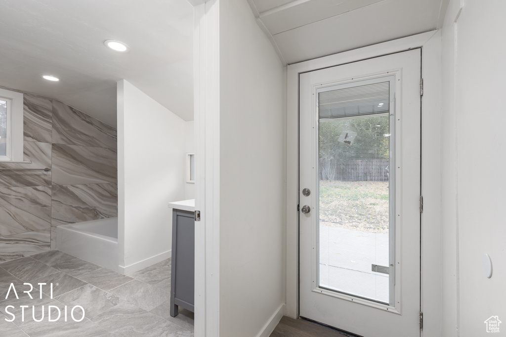 Doorway to outside featuring vaulted ceiling