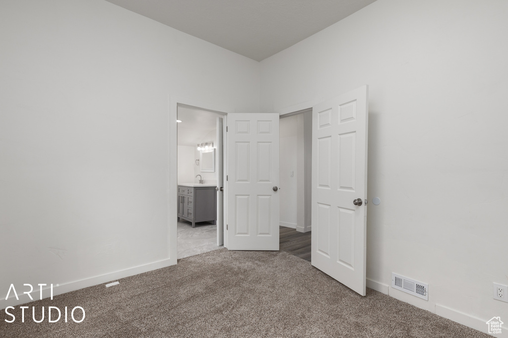 Unfurnished bedroom with ensuite bathroom and carpet floors