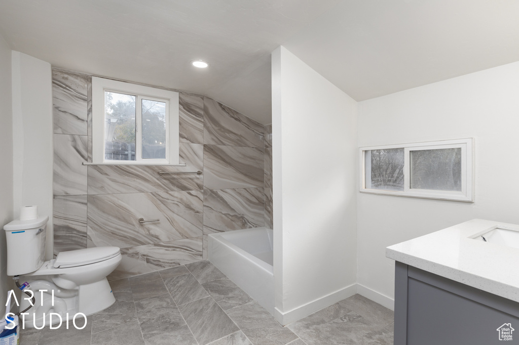 Full bathroom featuring independent shower and bath, vanity, vaulted ceiling, and toilet