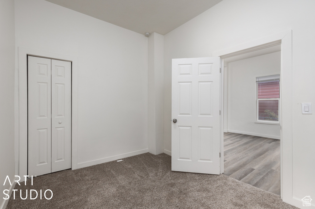 Unfurnished bedroom with a closet, carpet flooring, and lofted ceiling