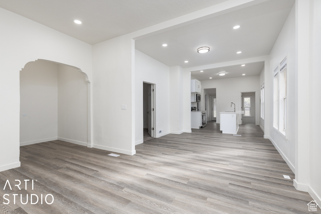 Unfurnished living room featuring sink and light wood-type flooring