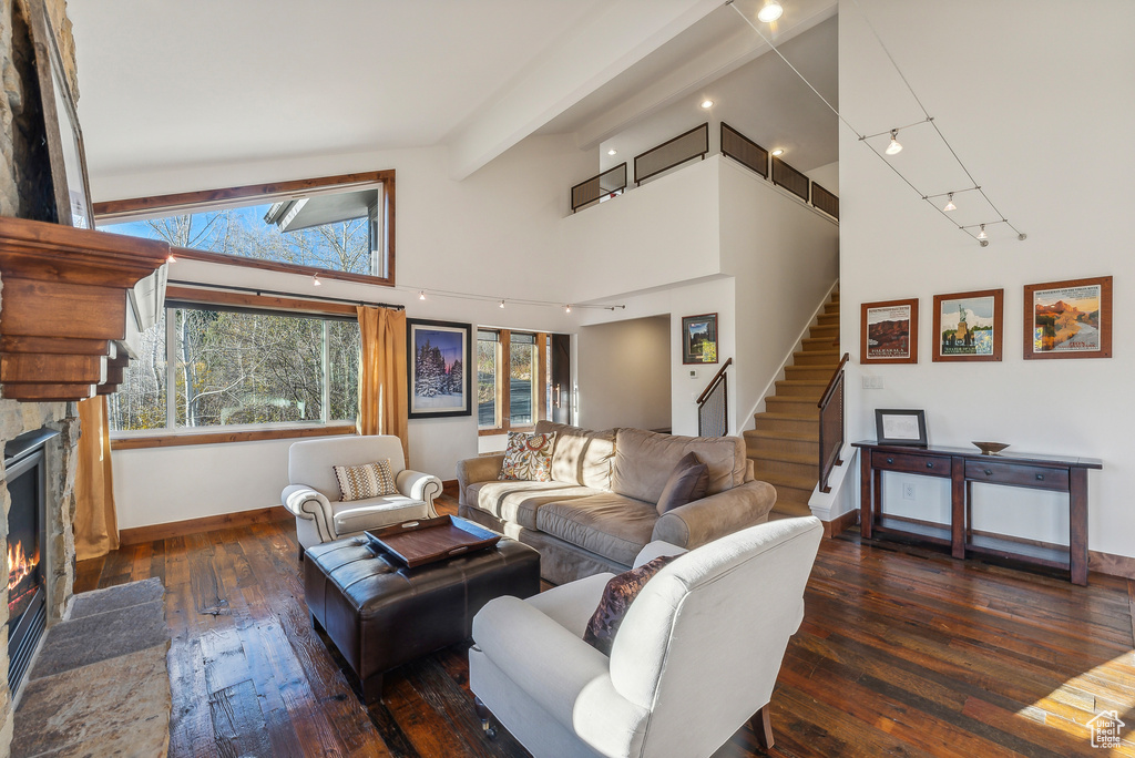 Living room featuring beam ceiling, a fireplace, high vaulted ceiling, and dark hardwood / wood-style flooring