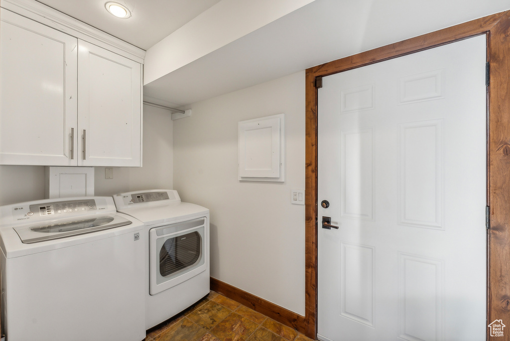 Clothes washing area featuring electric panel, cabinets, and washer and clothes dryer