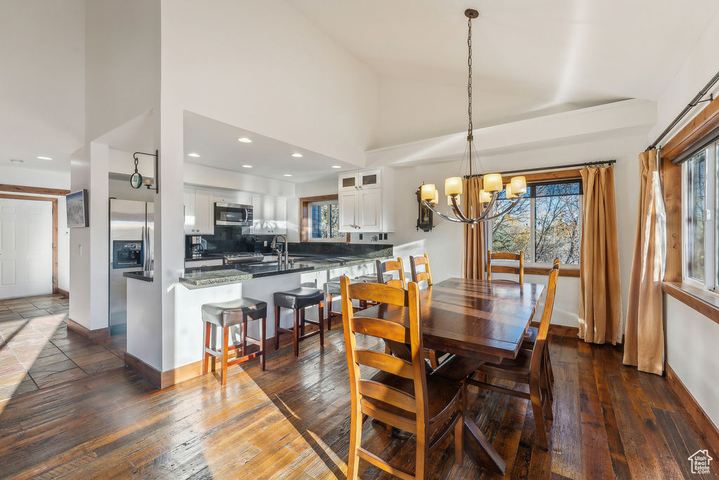 Dining space with a notable chandelier, high vaulted ceiling, sink, and dark hardwood / wood-style floors