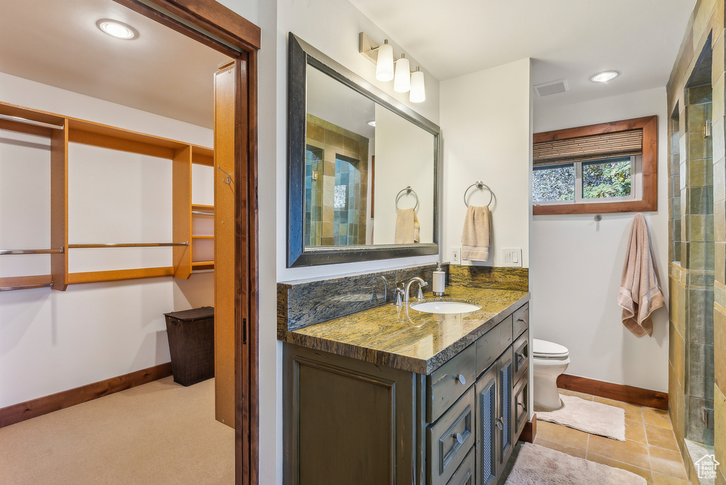 Bathroom with vanity, toilet, a shower with shower door, and tile patterned flooring