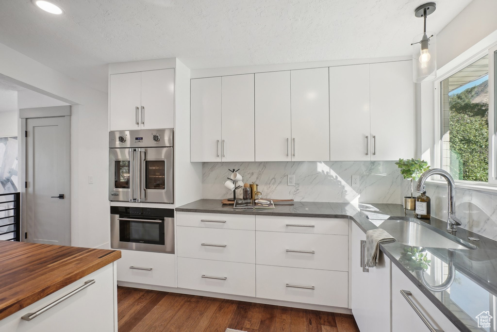 Kitchen with white cabinetry, sink, dark hardwood / wood-style floors, and stainless steel double oven