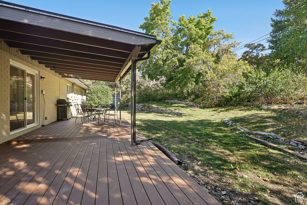 Wooden deck featuring a yard and a grill