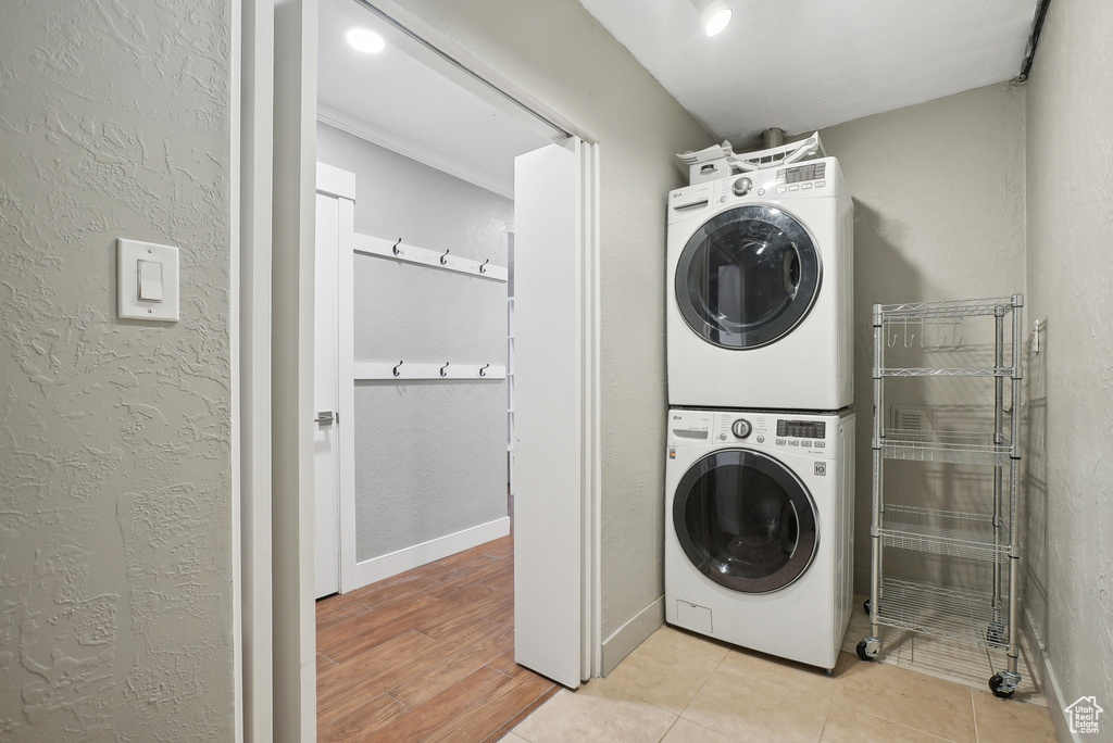 Laundry area with light hardwood / wood-style flooring and stacked washing maching and dryer