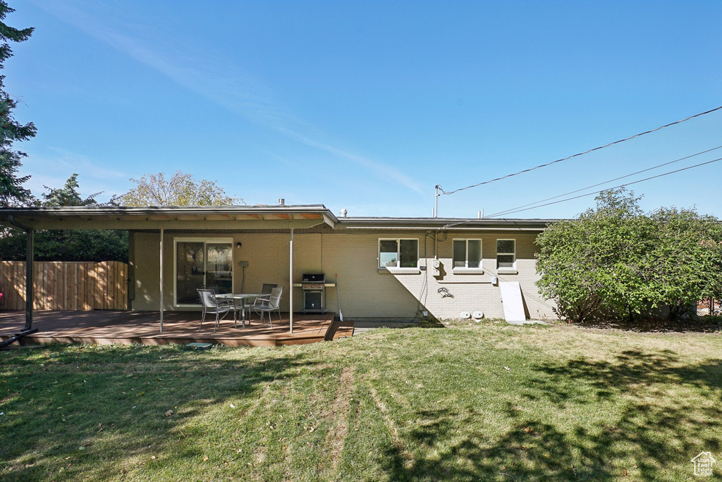 Rear view of house featuring a deck and a yard